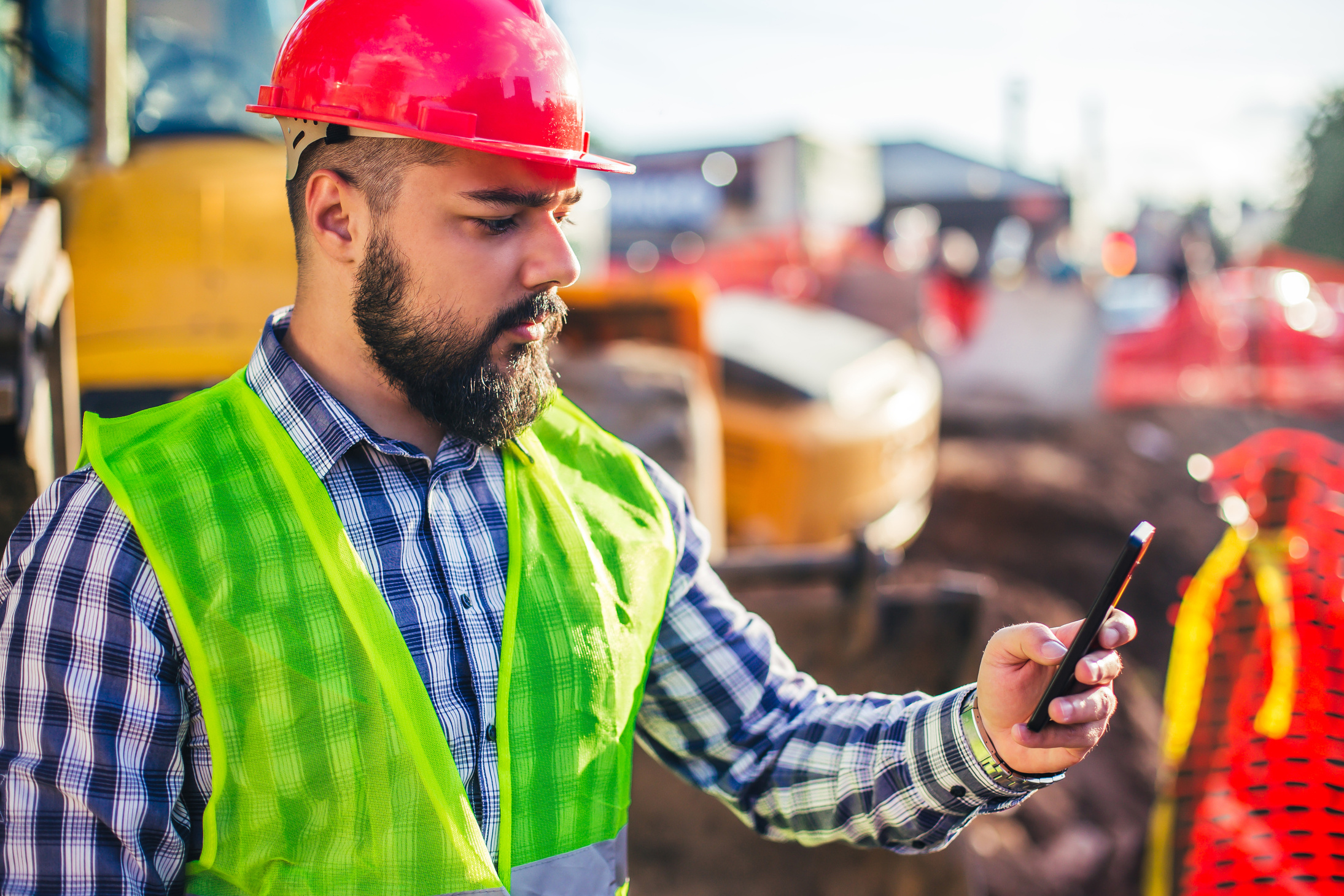 Construction worker checks cell phone.