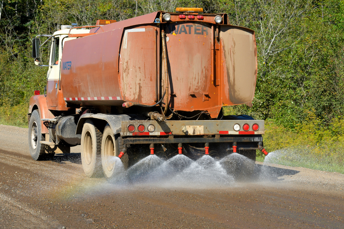 Water Truck Spraying Gravel Road to Suppress Dust and Prepare for Asphalting